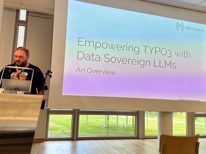 Das Bild zeigt Thomas Schöne bei den TYPO3 Developers Days 2024, der vor einer Folie mit dem Titel “Empowering TYPO3 with Data Sovereign LLMs - An Overview” steht.