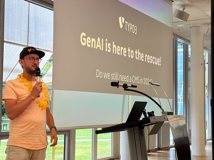 Benni Mack bei den TYPO3 Developer Days 2024 in Karlsruhe, der die Keynote zum Thema ‘GenAI is here to the rescue!’ hält. Die Präsentation ist im Hintergrund zu sehen.